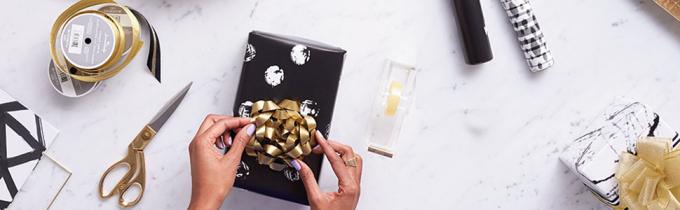 Oro y fuentes negras del papel de regalo por el sello incluyendo cinta, arcos, papel de embalaje y papel seda